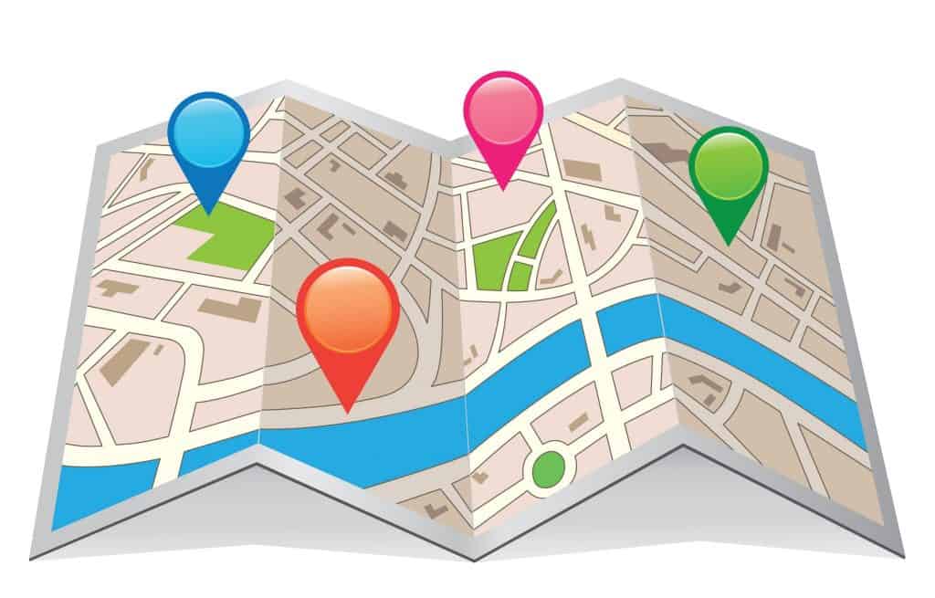 Illustration af et foldet kort med flere farverige placeringsmarkører i blå, rød, pink og grøn placeret på forskellige punkter. Kortet viser veje, vandområder og bygninger, og fremhæver nøglebutikker og onlinevirksomheder.