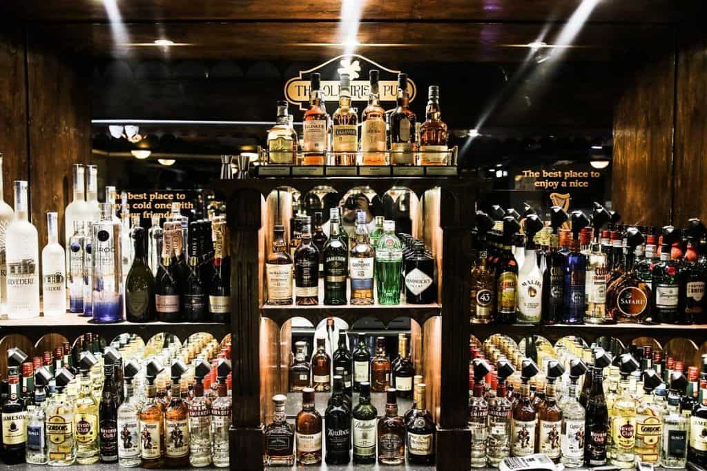 En velassorteret bar med et udvalg af spiritusflasker, herunder whisky, vodka og vin, arrangeret på hylderne. Skiltning over og omkring baren fremhæver etablissementets indbydende atmosfære.