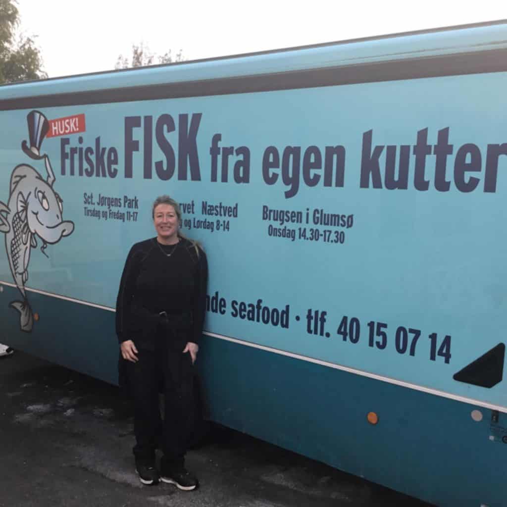 Byliv.nu: En person, der står foran en blå fiskebil med teksten 