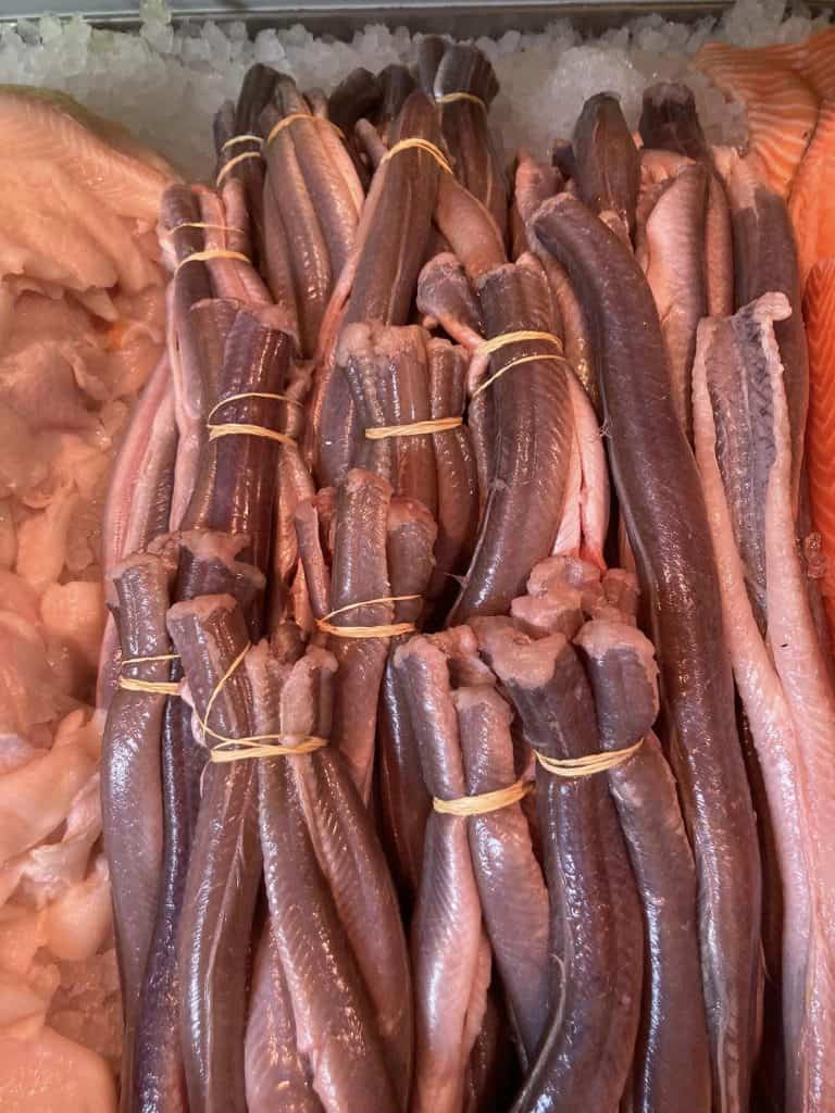 Byliv.nu: Bunter af rå fiskefileter bindes sammen med gule gummibånd, vist på en isleje.