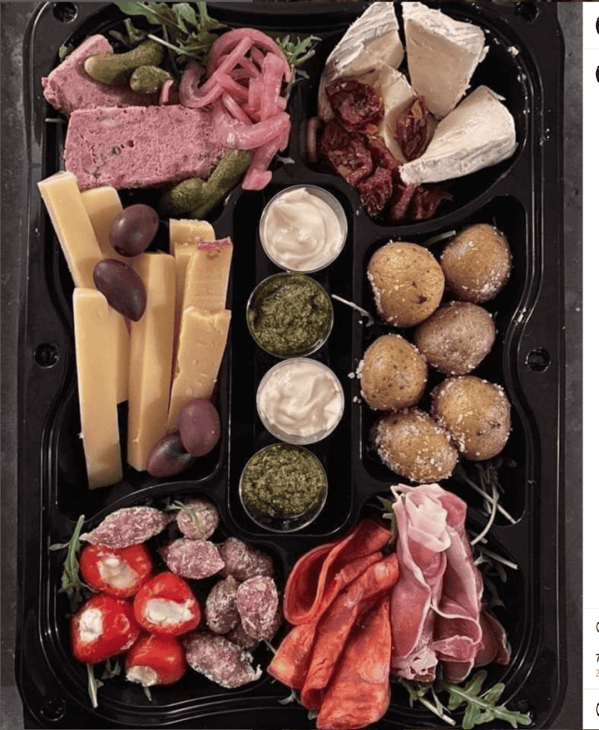Byliv.nu: En sort bakke med sektioner indeholdende diverse oste, speget kød, fyldte peberfrugter, oliven, pickles, soltørrede tomater, pesto og dipsauce.