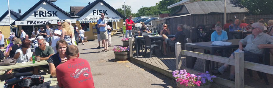 Byliv.nu: Folk sidder og står uden for en fiskerestaurant med skilte, hvor der står
